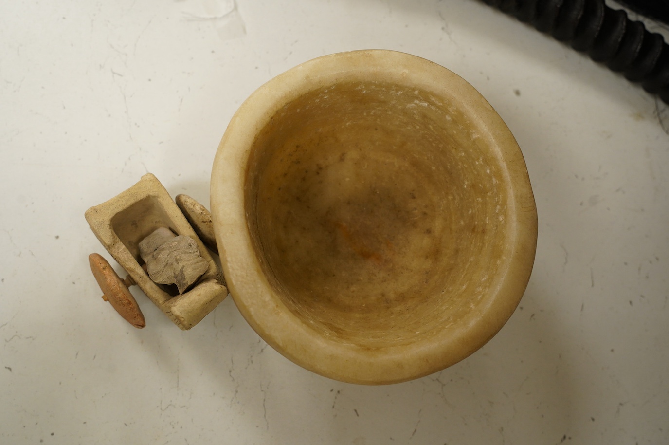 An alabaster mortar, possibly Ancient Egyptian, 17cm diameter, the handles ground off and a terracotta figure with chariot, possibly Mesopotamian. Condition - fair, restoration to chariot